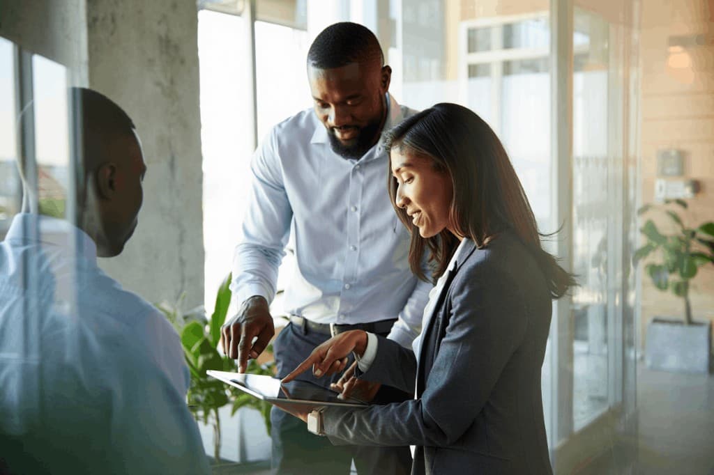 Team members collaborating around a tablet in a modern office